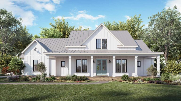 A front view of a modern farmhouse-style home with a classic and inviting design. The exterior is finished with white board and batten siding, complemented by a light gray metal roof. The house features a large, covered front porch supported by white columns, leading to double front doors with glass panels. The windows are large and framed in black, adding contrast to the light exterior. The landscaping includes a neatly manicured lawn, shrubs, and colorful flower beds, with mature trees surrounding the home, all set against a bright, sunny sky.